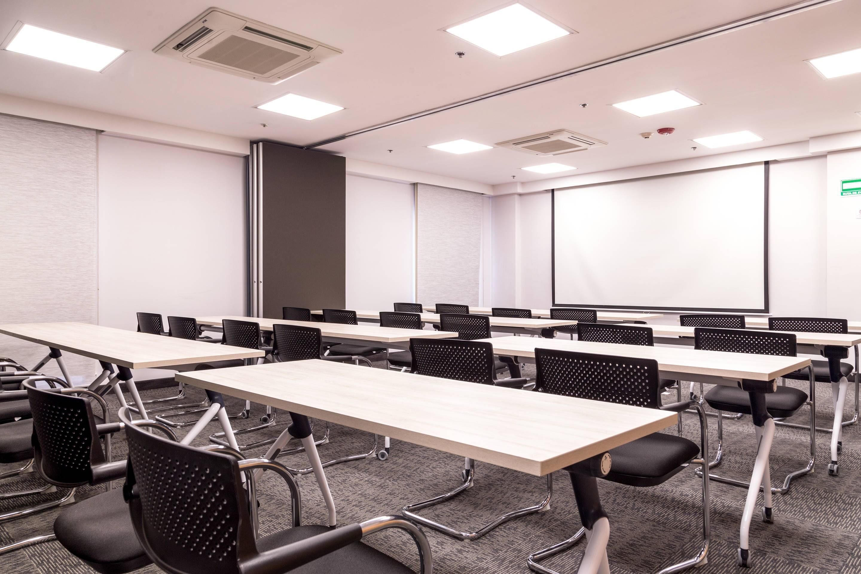 A conference room with multiple tables and chairs, a whiteboard, and a projector screen.