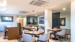 A modern dining area with multiple tables and chairs, a reception desk, and artwork on the walls. - Comfort Inn Hermosillo Aeropuerto (Hermosillo)