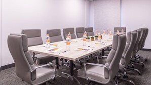 A conference room with a long table, grey chairs, water bottles, and small potted plants. - Comfort Inn Hermosillo Aeropuerto (Hermosillo)