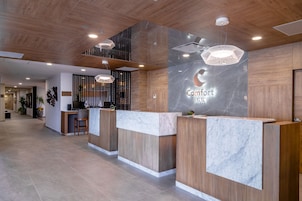 Zona de recepción de hotel con mostradores de madera, detalles de mármol e iluminación moderna.