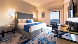 A hotel room with a bed, bedside table, desk, chair, and a large window offering a view. - Comfort Inn Hermosillo Aeropuerto (Hermosillo)