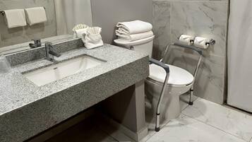 Ein modernes Badezimmer mit einer Granit-Arbeitsplatte, einem Waschbecken, einer Toilette und einer Duschkabine.