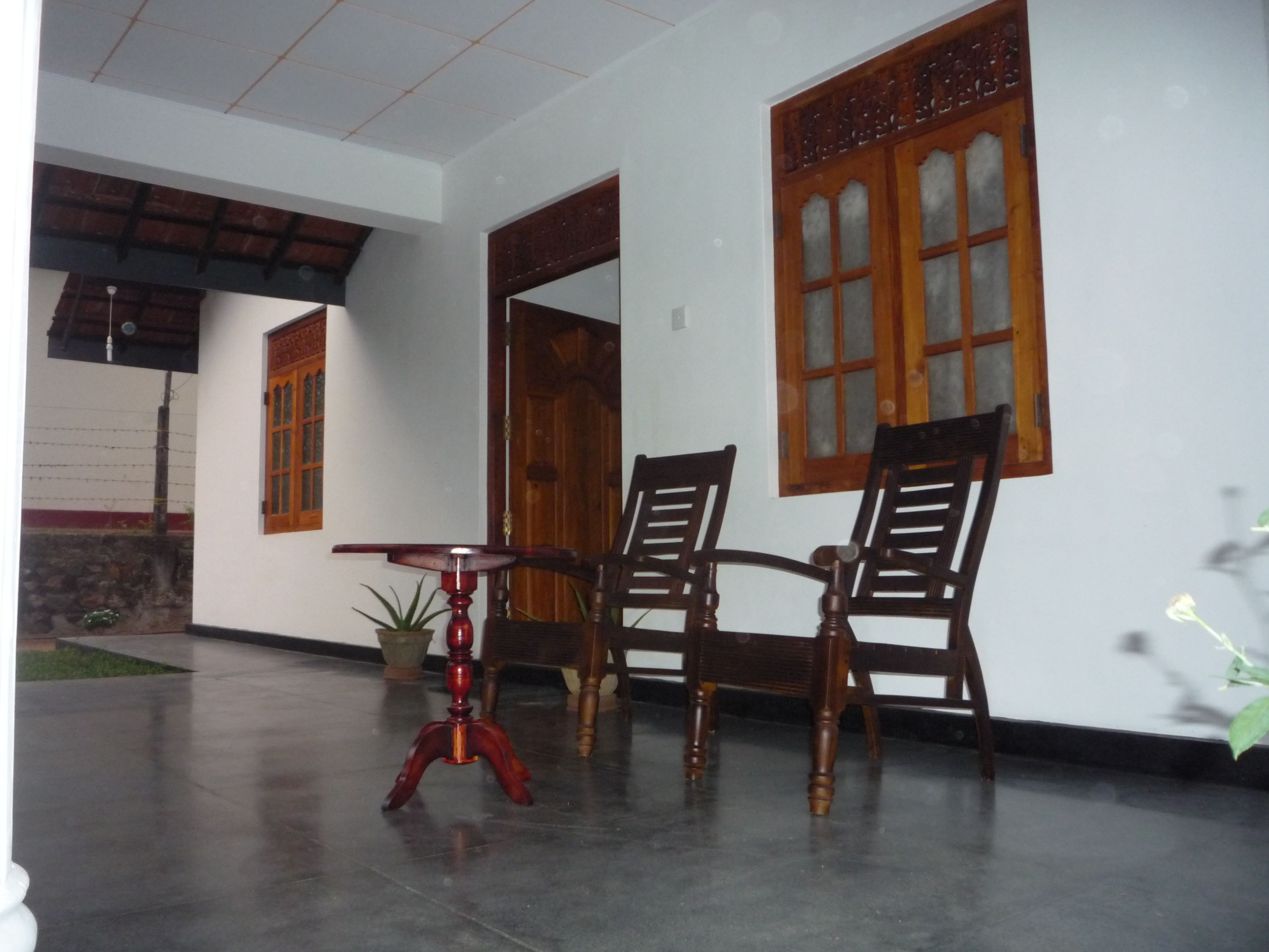 A room with a table and two chairs, a potted plant, and a wooden door.