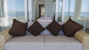 Una habitación con vista al mar, un sofá con cojines marrones y un ventanal de vidrio que da a la playa.