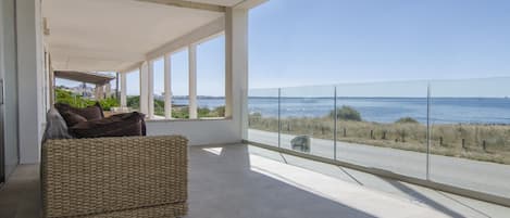 A spacious balcony with a clear view of the sea and a distant cityscape.
