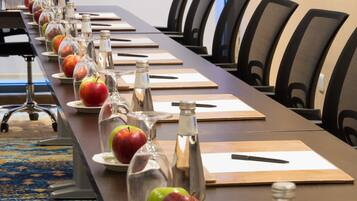 A conference table with apples, water bottles, and notepads in a meeting room.