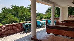 An outdoor patio area with wooden benches and blue chairs, surrounded by a lattice fence and greenery. - Economy double room - close to the Velika Plaza for cheap price (UL)