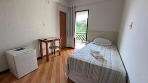 Un dormitorio con una cama, un escritorio, una silla y un refrigerador pequeño.