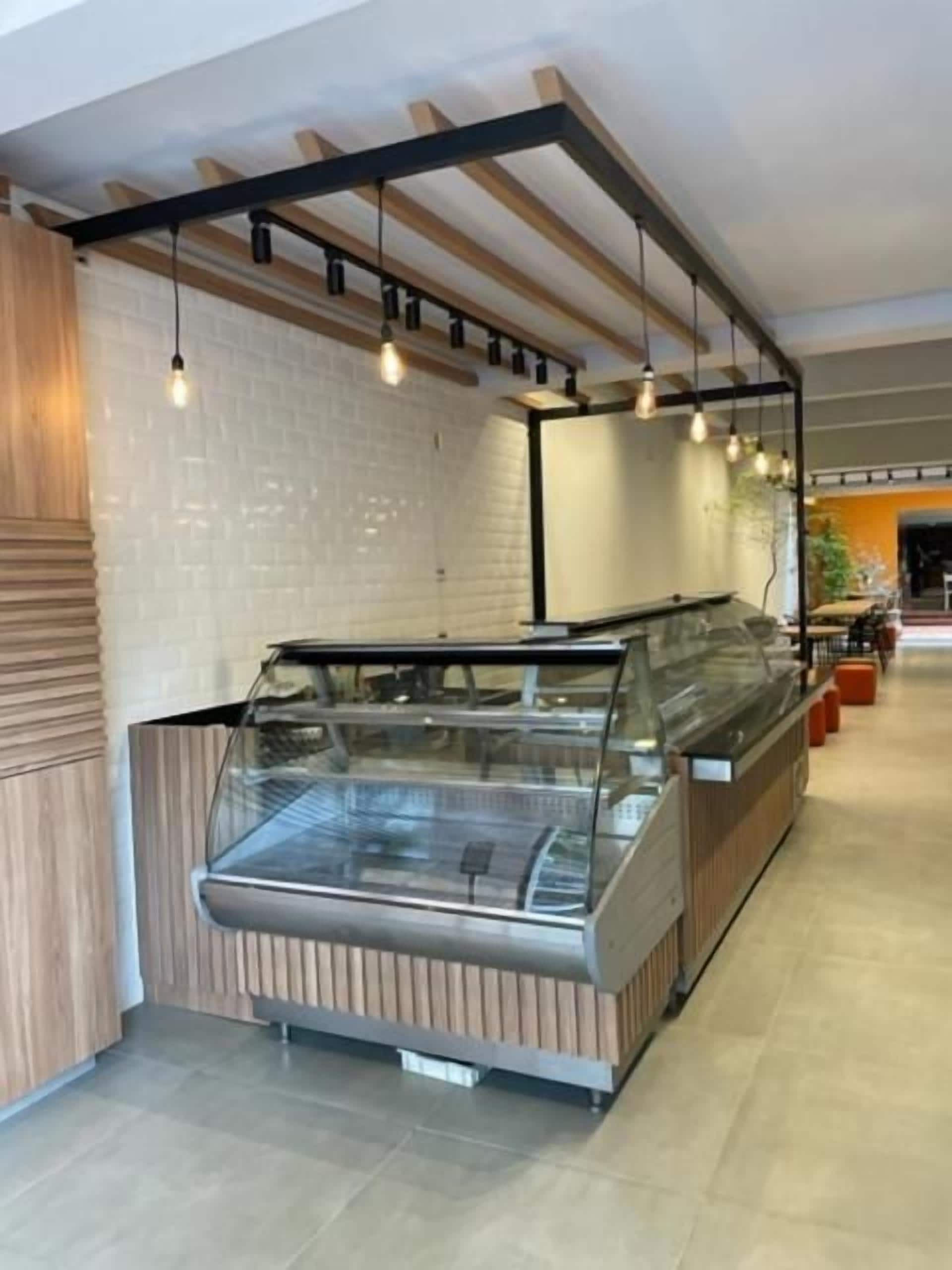 Un área moderna de exhibición de alimentos con un vitrina de vidrio, paneles de madera e iluminación colgante.