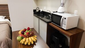 A compact kitchenette with a microwave, a blender, and a fruit bowl on a wooden table. - Flats Requinte Gramado (Gramado)
