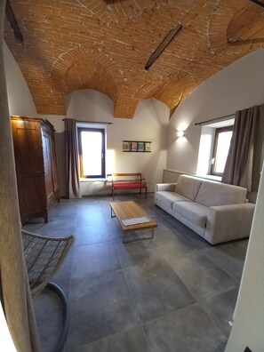 A spacious living room with a high wooden ceiling, a sofa, a red bench, and a wooden cabinet. - Villa Lavanda Tranquility and relaxation. (Lequio Tanaro)