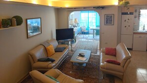 A living room with a sofa, coffee table, TV, and a kitchen area visible through an open doorway. - Casa "MANUELA" Feel at home in La Paz - Vivienda Vacacional (Puerto de la Cruz)