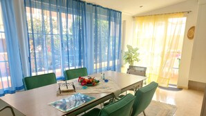 A dining area with a table set for four, green chairs, and a potted plant on the windowsill. - Casa "MANUELA" Feel at home in La Paz - Vivienda Vacacional (Puerto de la Cruz)