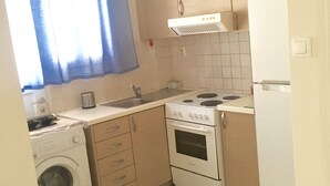 Cocina compacta con lavadora, estufa, lavabo y armarios.
