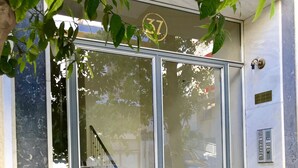 Entrada de un edificio con puerta de vidrio, una escalera en el interior y un cartel con el número 37 encima de la puerta.