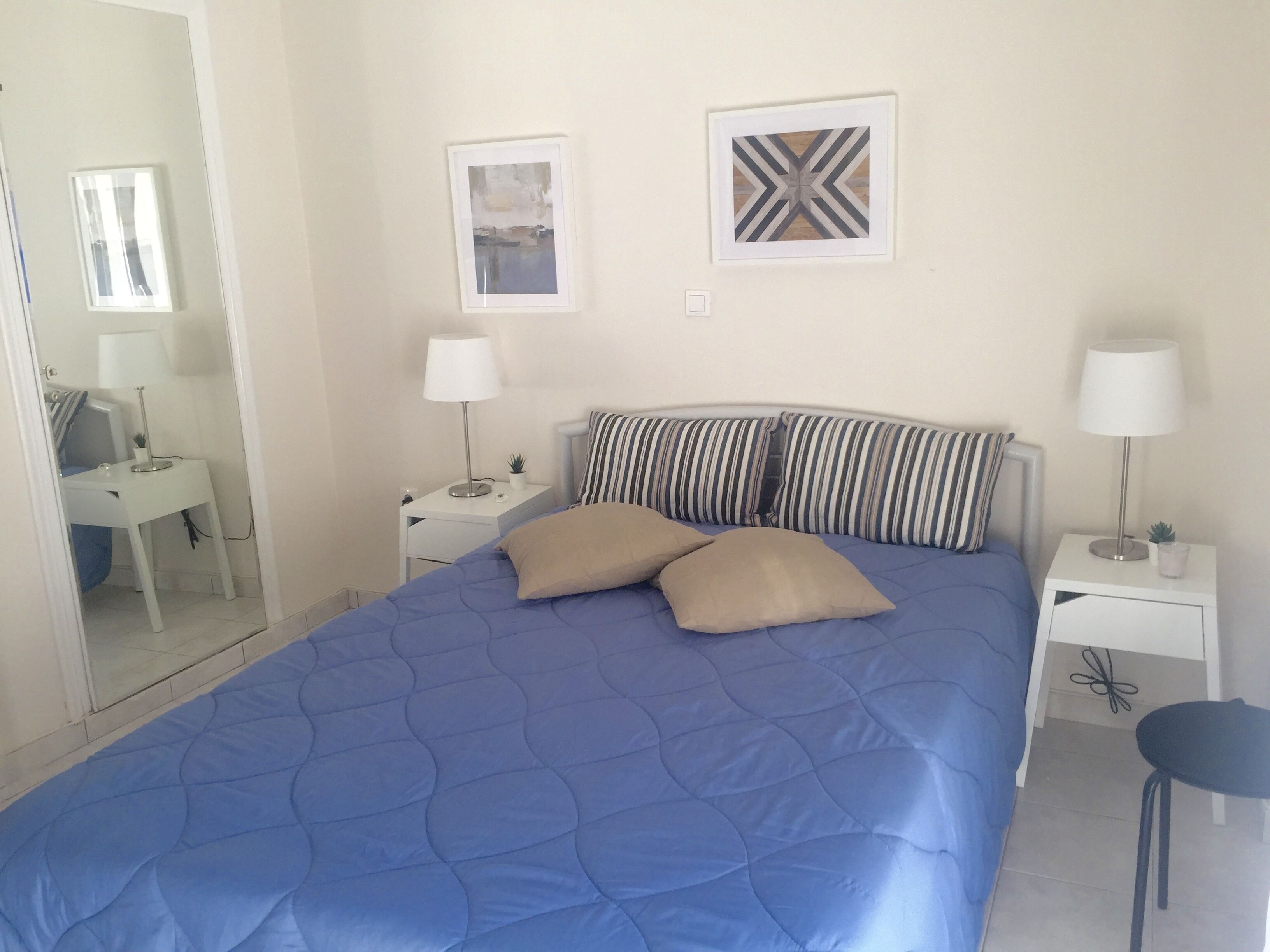 Un dormitorio con una cama grande, dos mesitas de noche con lámparas, un escritorio pequeño y una silla.