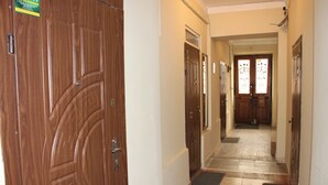 A hallway with wooden doors, a tiled floor, and a door with a glass panel.