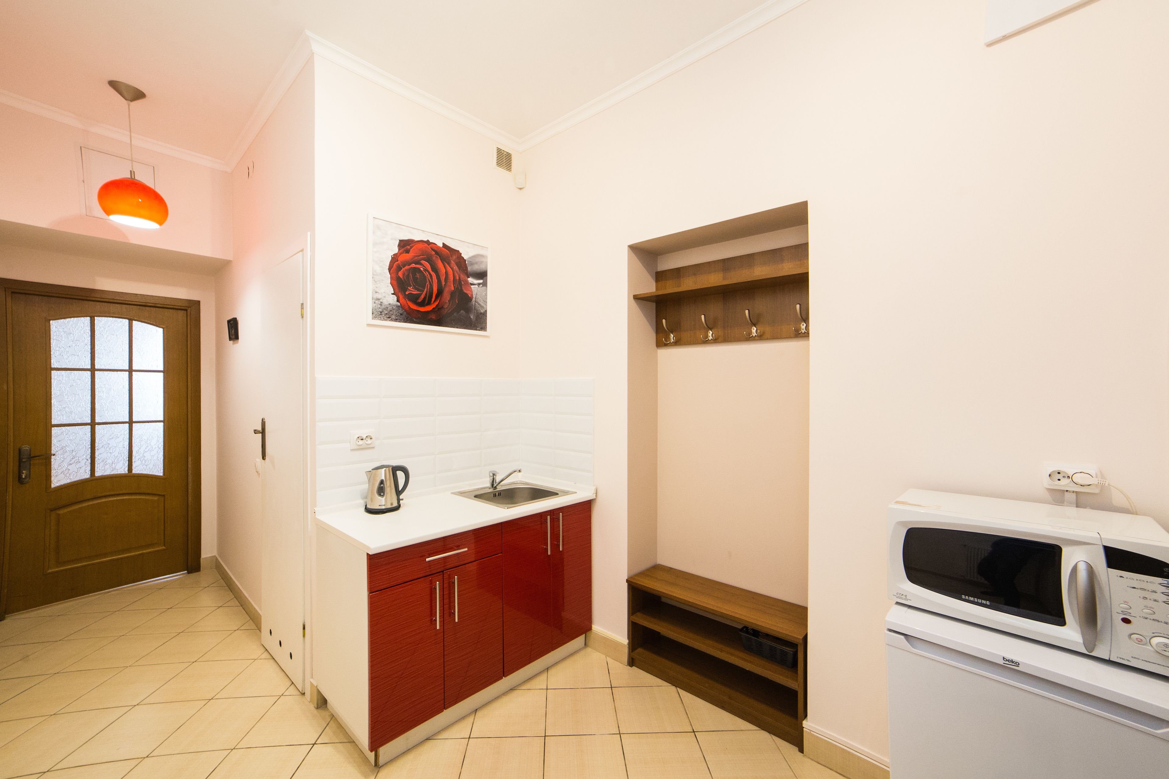 A compact kitchen with a microwave, sink, and red cabinets.
