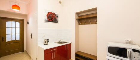 A compact kitchen with a microwave, sink, and red cabinets.