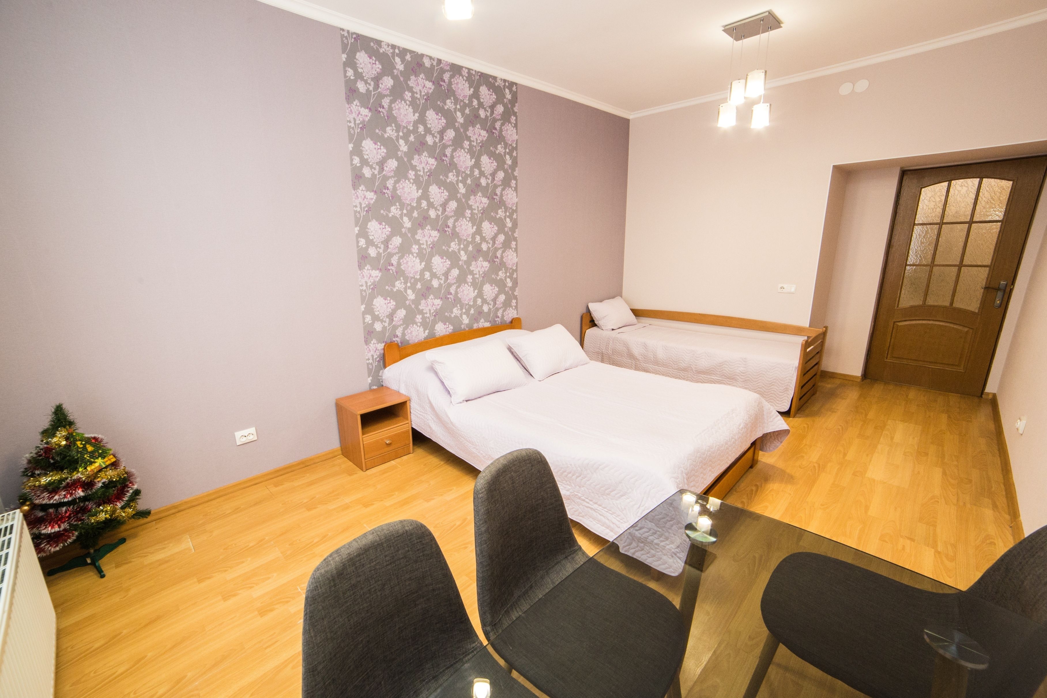 A bedroom with two beds, a small table, and a Christmas tree.