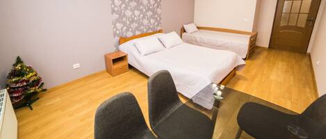 A bedroom with two beds, a small table, and a Christmas tree.