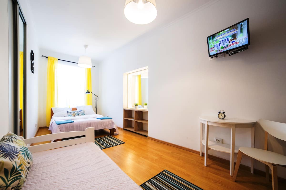 Una habitación de hotel con cama, escritorio, silla, televisor y espejo.