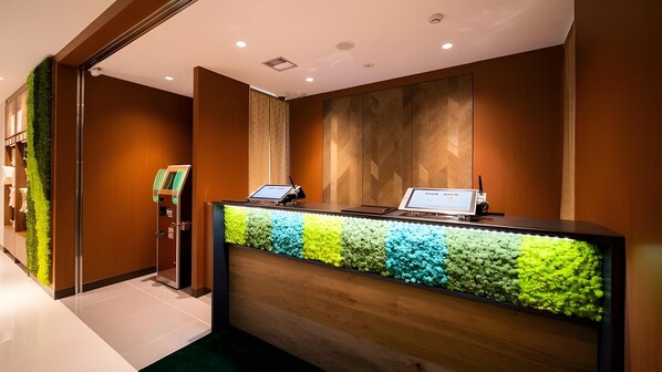 A reception desk with a digital screen, a self-service kiosk, and a vertical garden. - Super Hotel Yamagata Tsuruoka (Tsuruoka)
