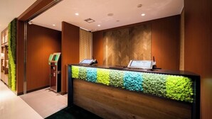 A reception desk with a colorful moss wall, a digital display, and a self-service kiosk. - Super Hotel Yamagata Tsuruoka (Tsuruoka)