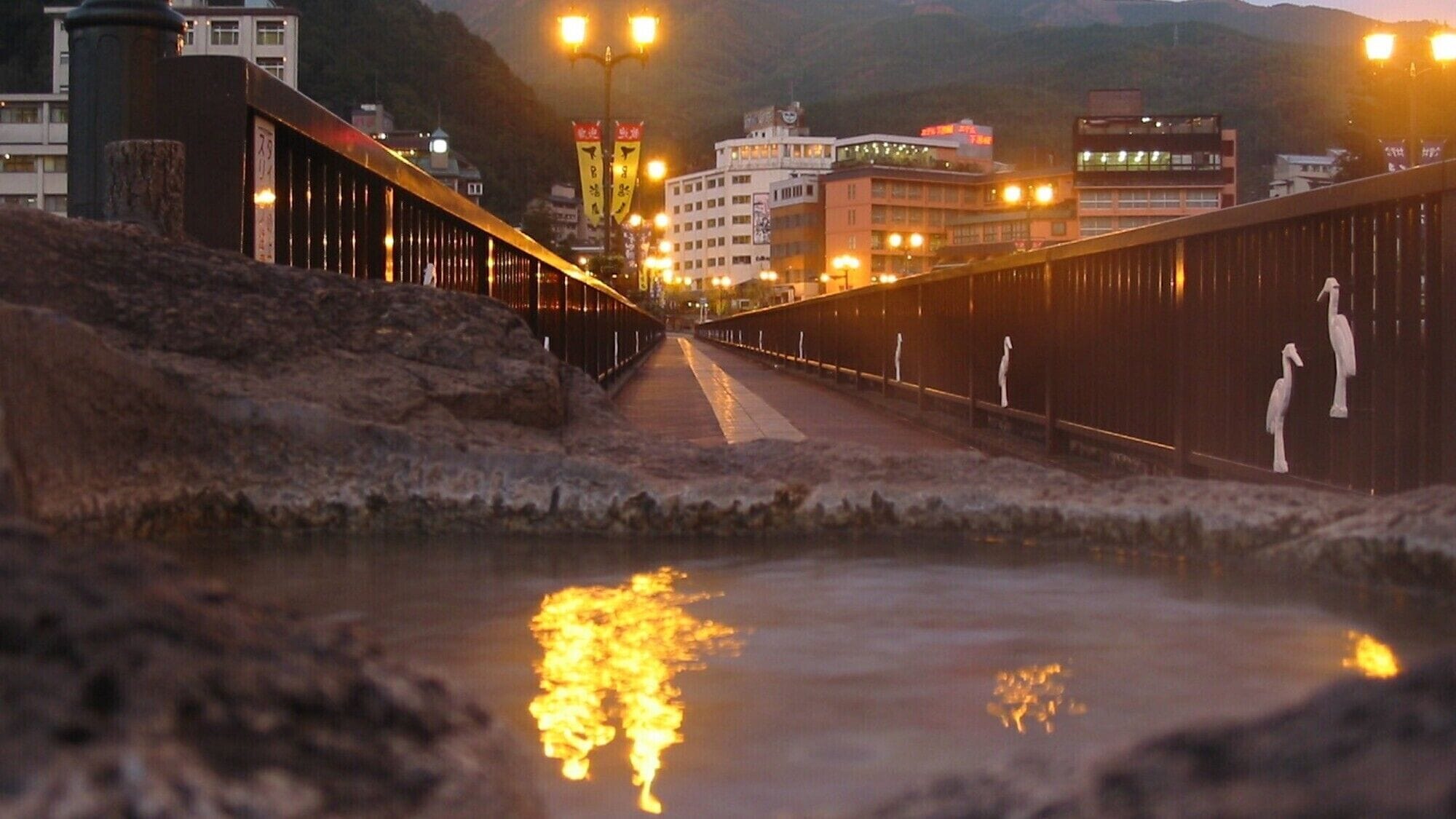 A bridge with a railing, a pathway, and buildings in the background.