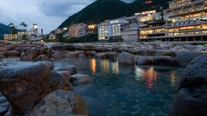 A hotel with multiple floors, large windows, and a view of a rocky water feature. - Izumiso <gifu Gero City> (Gero)