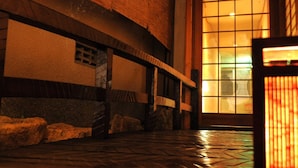 Um corredor com piso de pedra, porta de madeira e janela com iluminação acolhedora.