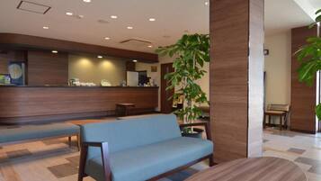 A reception area with a wooden reception desk, a blue sofa, and a round table.