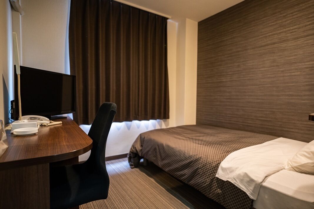Een hotelkamer met een bed, een bureau met telefoon en een televisie.