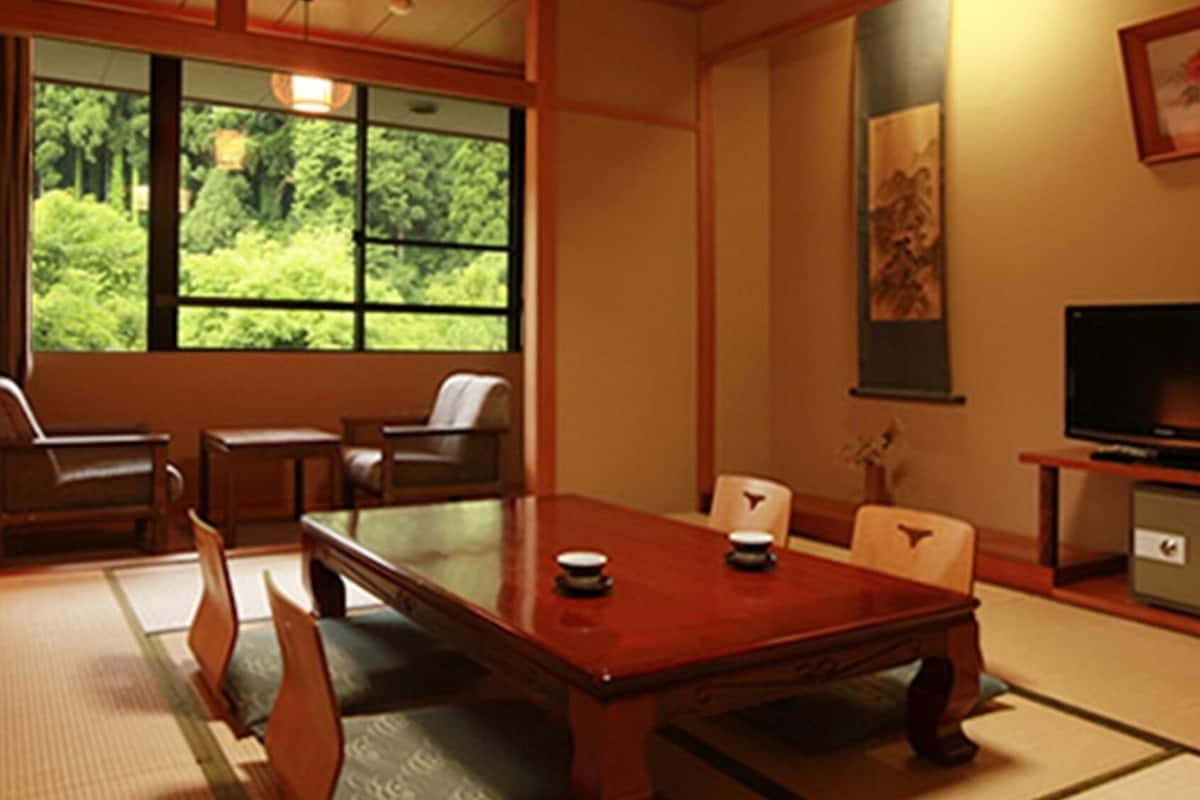A traditional Japanese-style room with tatami flooring, a low table, and seating.