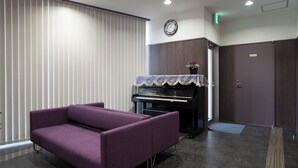 A room with a purple sofa, a piano, a clock, and a door. - Hotel Murakami (Nikko)