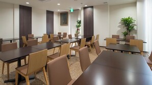 A conference room with multiple tables and chairs, a large window with curtains, and a plant in the corner. - Hotel Murakami (Nikko)