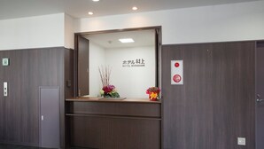 A reception desk with a mirror, a sign reading "Hotel Murakami," and two flower arrangements. - Hotel Murakami (Nikko)
