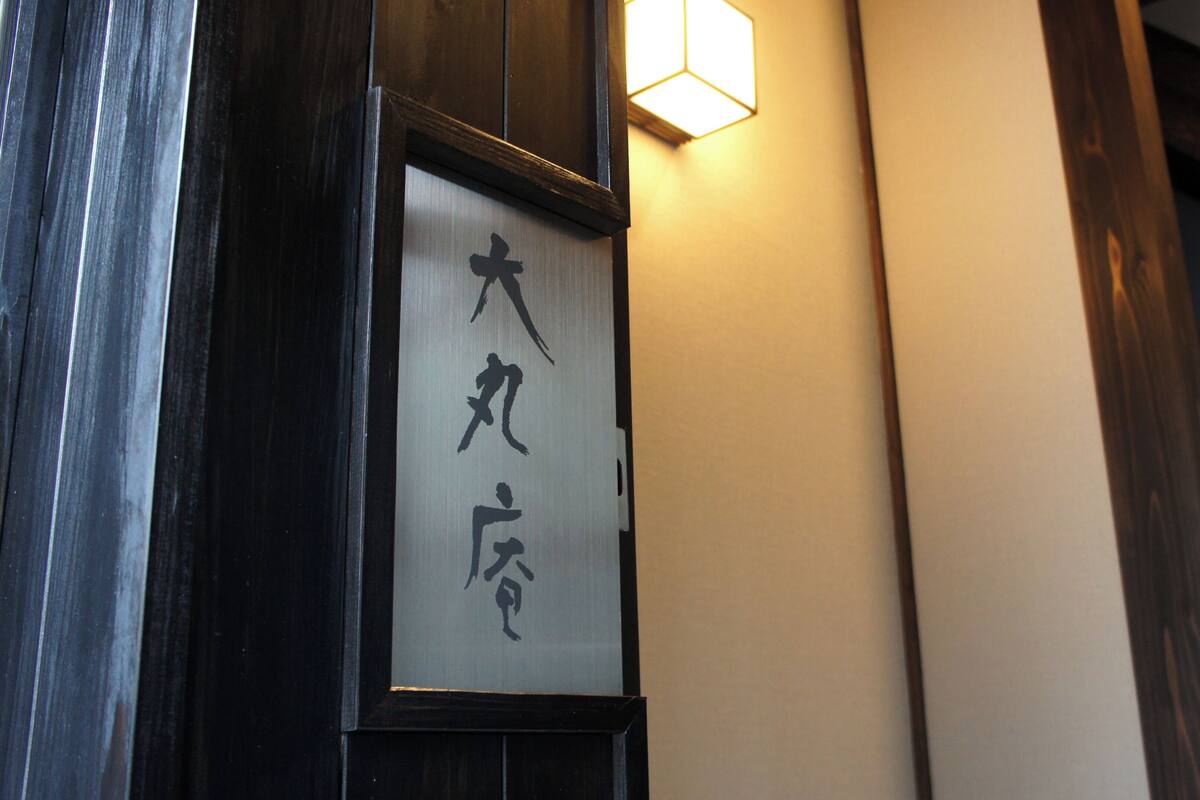 A traditional Japanese-style building with a wooden door and a sign with Japanese characters.