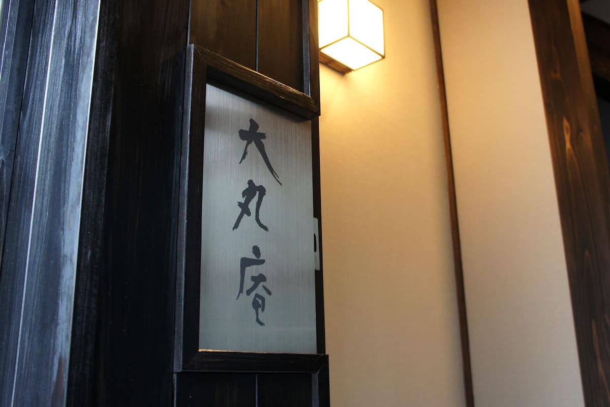 A traditional Japanese building with a wooden door and a sign with Japanese characters.