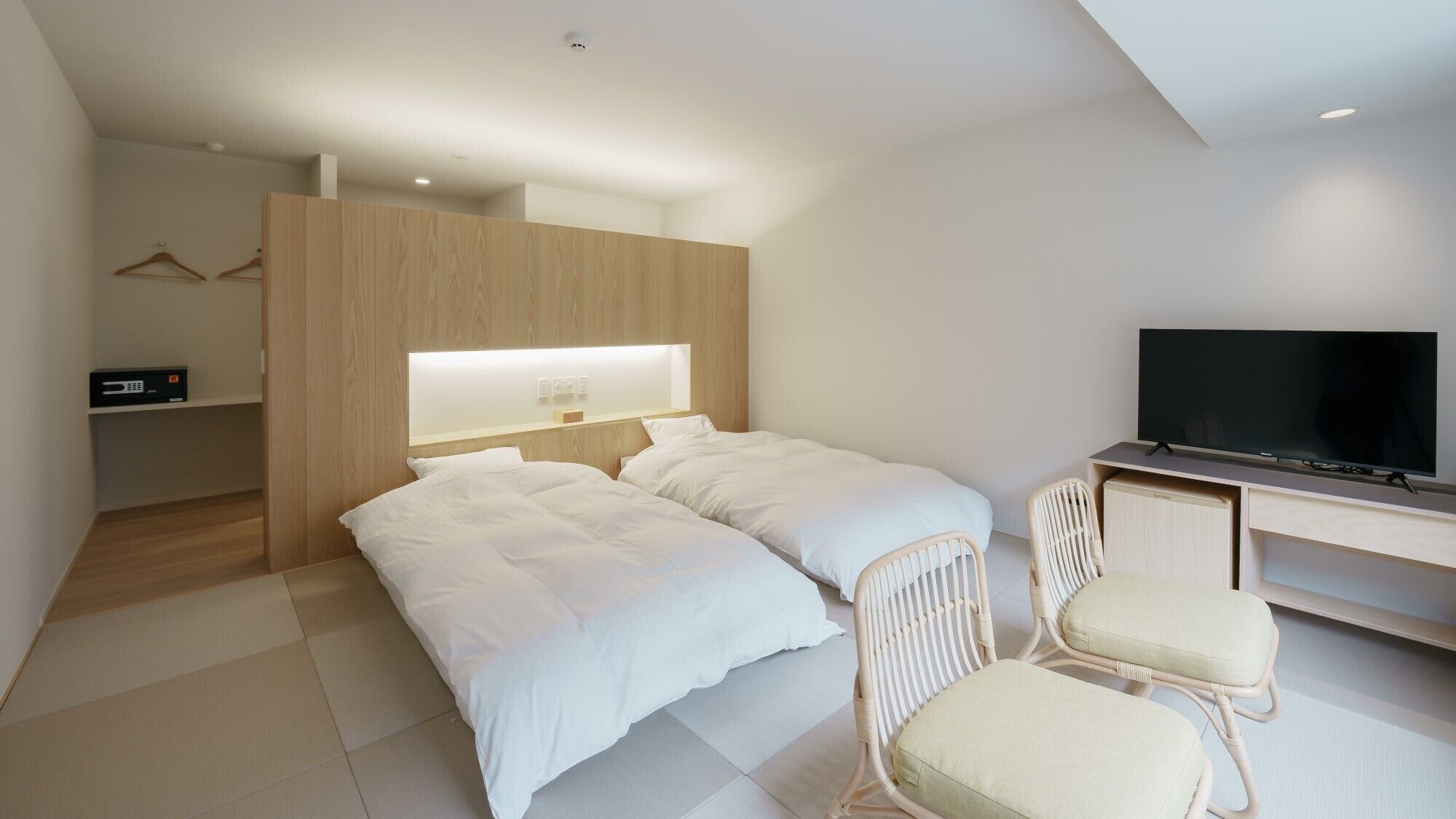 A modern hotel room with two beds, a TV, a desk, and a chair.