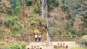 A wooden deck with picnic tables and a railing overlooking a waterfall. - Mimata Onsen Nagomi Yuyado Kanagi (Hamada)
