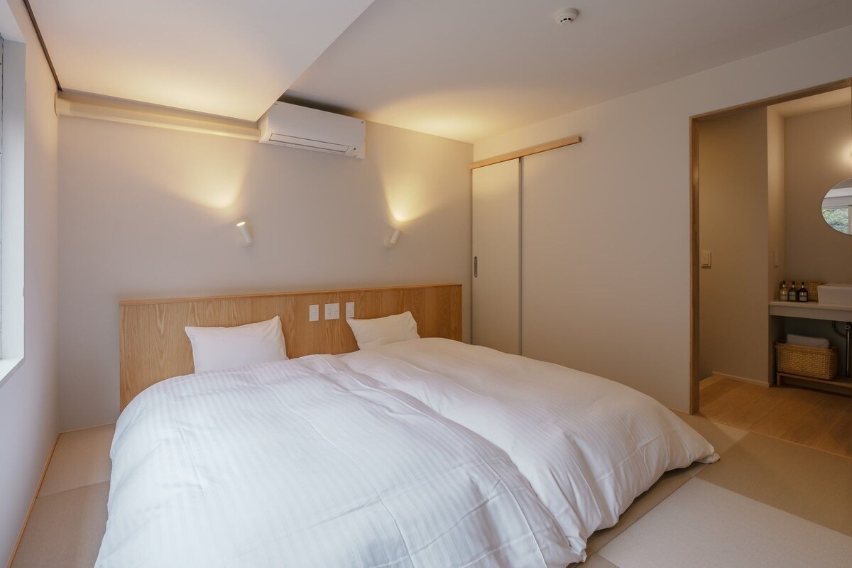 Un dormitorio con una cama grande, una ventana, un equipo de aire acondicionado y un armario.