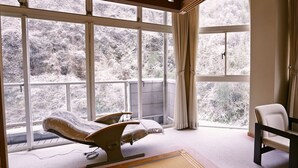 A room with a bed, a chair, and large windows with a view of trees. - Mimata Onsen Nagomi Yuyado Kanagi (Hamada)