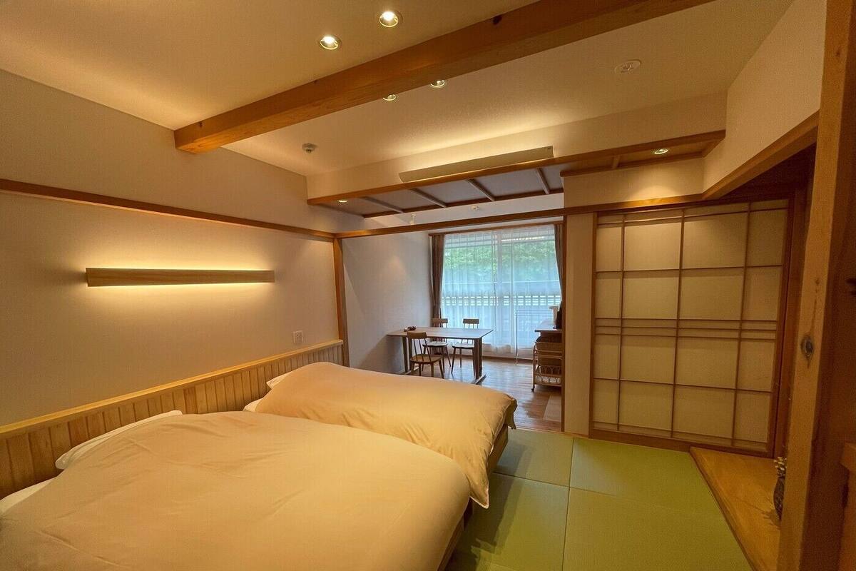 A room with two beds, a small table, and a sliding door.