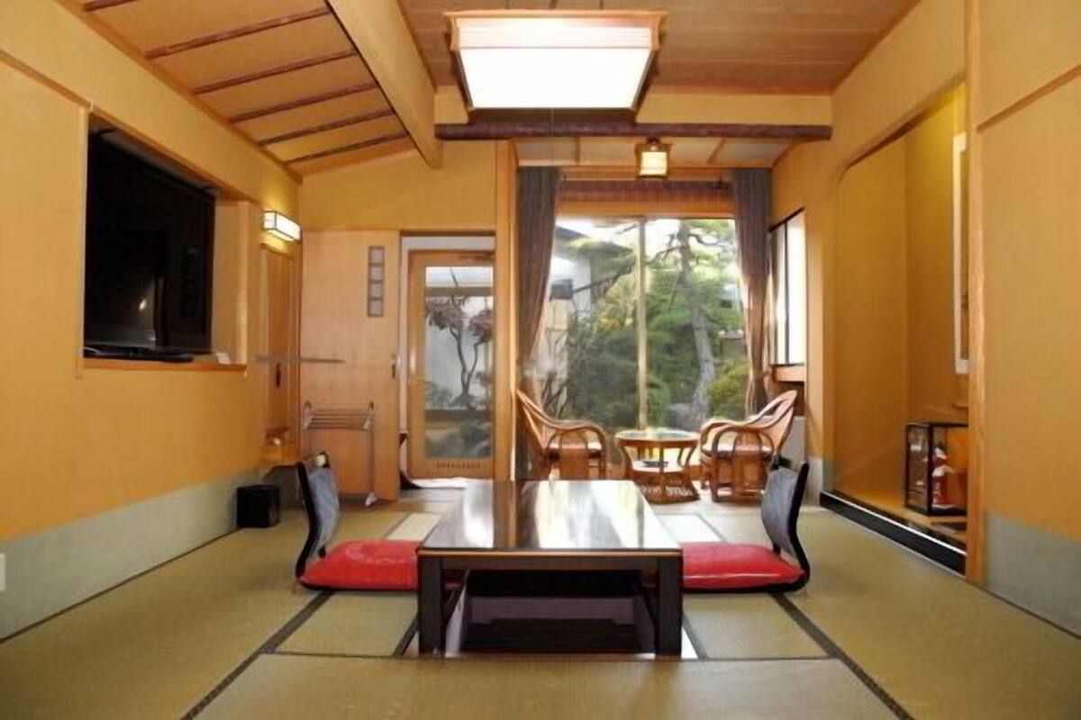 Um quarto tradicional japonês com tatames, uma mesa baixa e móveis de madeira.