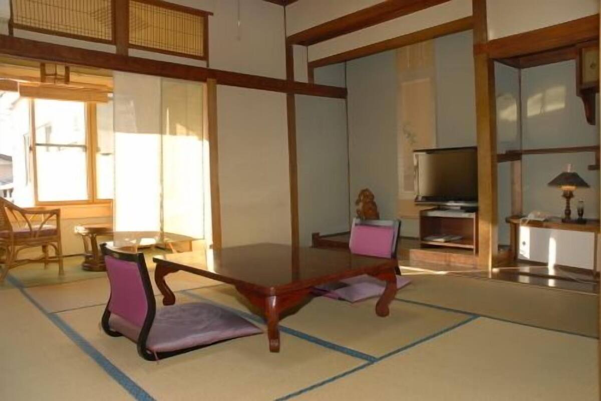 Quarto japonês tradicional com tatames, uma mesa de madeira baixa e uma televisão.