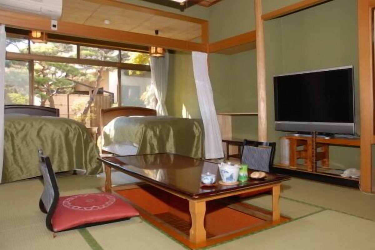 Quarto com uma cama, televisão, mesa e futon.