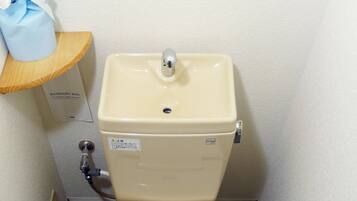 A toilet with a control panel, a sanitary bag dispenser, and a toilet paper holder.