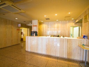 Hotellin vastaanottotiski marmoripöytätasolla, opastekyltti ja laatoitettu lattia.