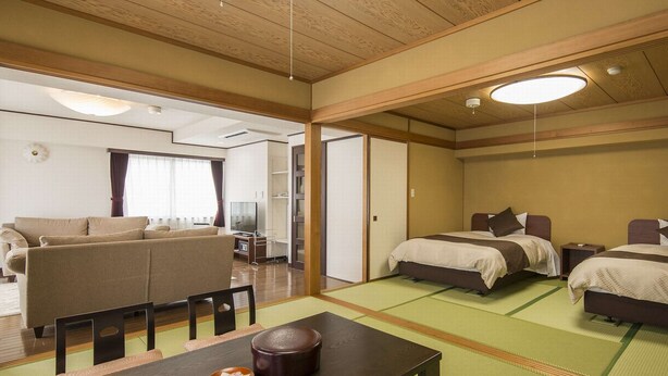 A traditional Japanese-style room with tatami flooring, a low wooden ceiling, and a sofa. - Hotel Showa Club (Atami)